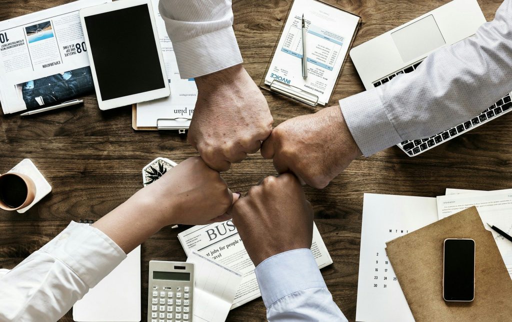 Cuatro personas juntando puños en oficina de administración pública