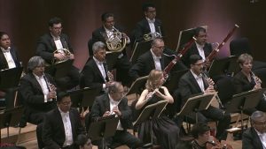 Músicos tocando instrumentos de viento en concierto.