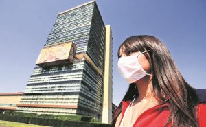 Una estudiante usando cubrebocas enfrente de edificio de rectoría de UNAM