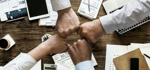 Cuatro personas juntando puños en oficina de administración pública
